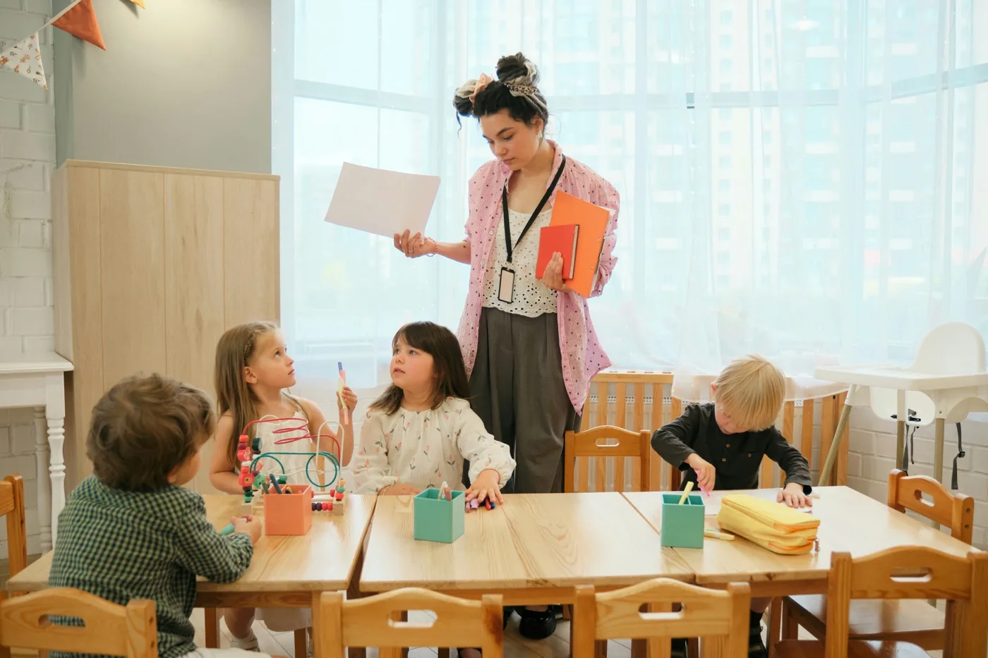 A teacher working with young students at a classroom table