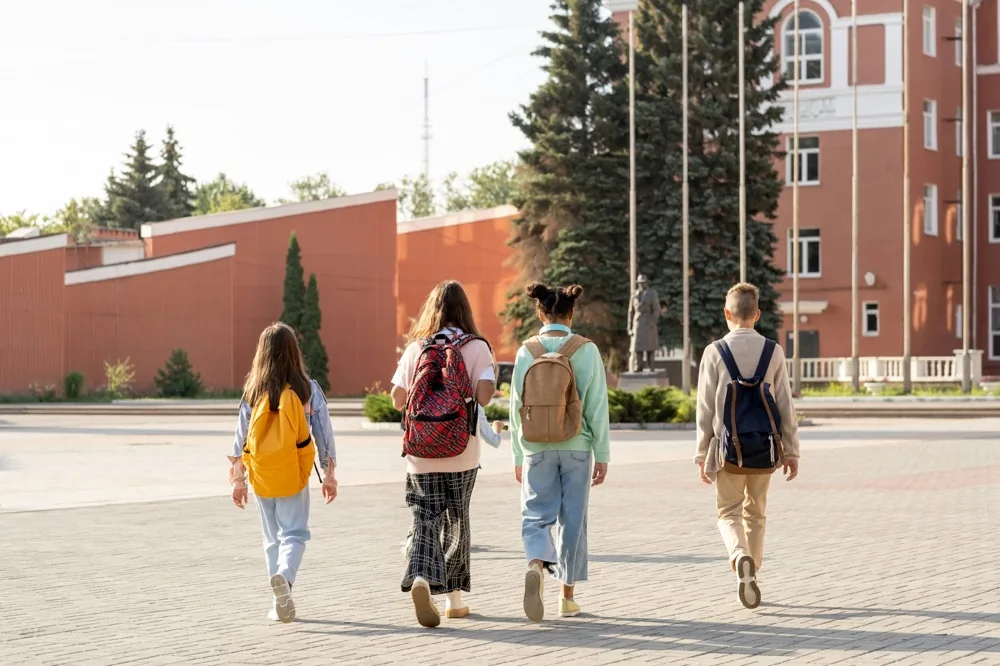 Students walking away down a school corridor with their backpacks